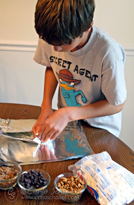tween in blue shirt rolling candy chips in a sugar cone with foil