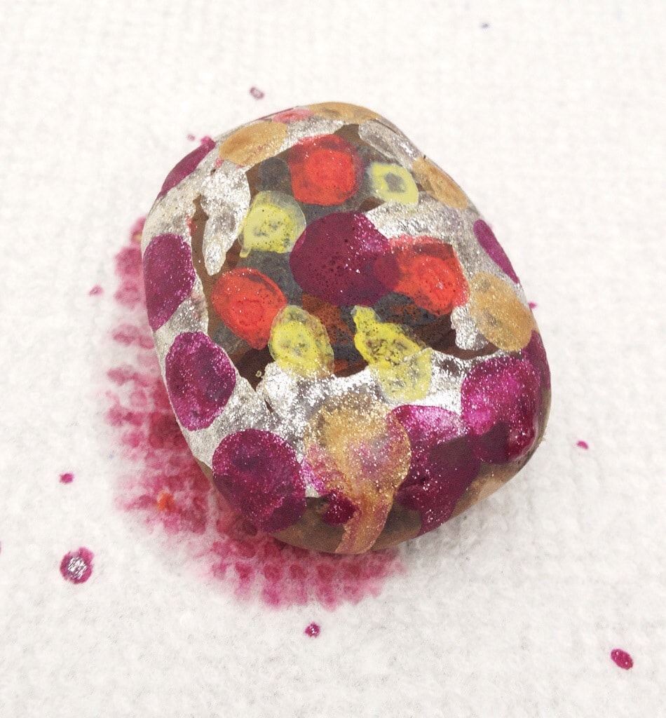 Make melted crayon rock kids craft Brown rock covered with multicolored melted crayon wax, sitting on white paper towel.