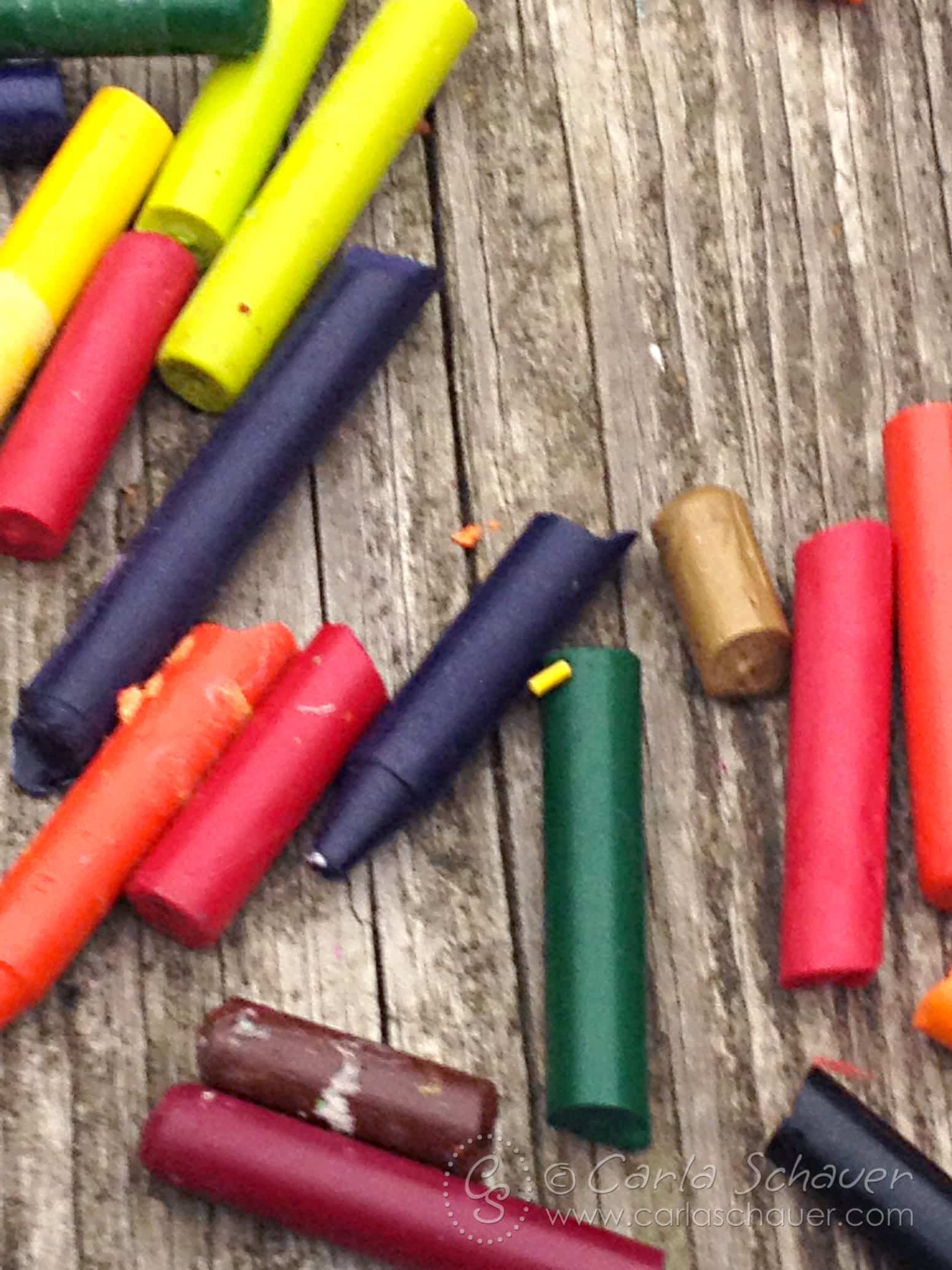 Broken crayon pieces on wood table.