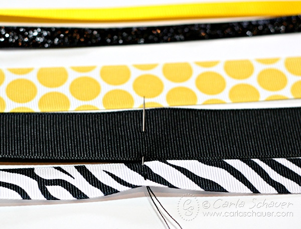 Horizontal yellow, black and white ribbons being sewn together to make athletic bow.