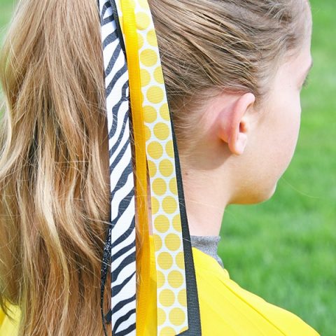 Girl with ponytail wearing fastpitch softball ponytail streamers.