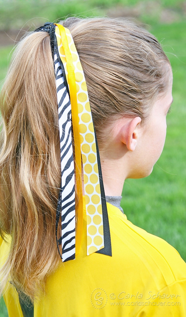 Girl in yellow wearing yellow, black, and white.DIY pony-o streamer bows for fastpitch softball.
