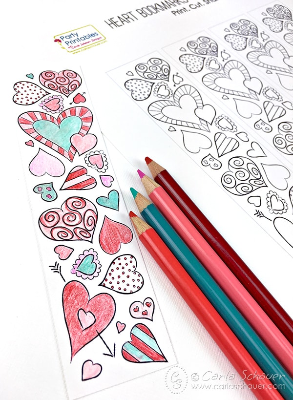 Printed heart-patterned bookmarks, one in color, with red, pink, and teal colored pencils on white background.