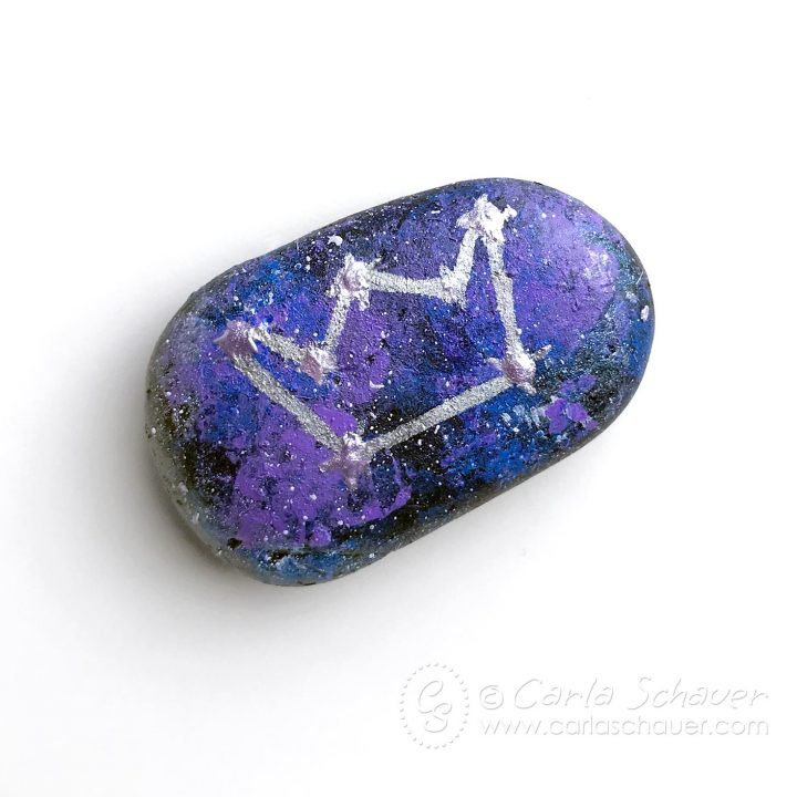 Rock painted with galaxy on white background.