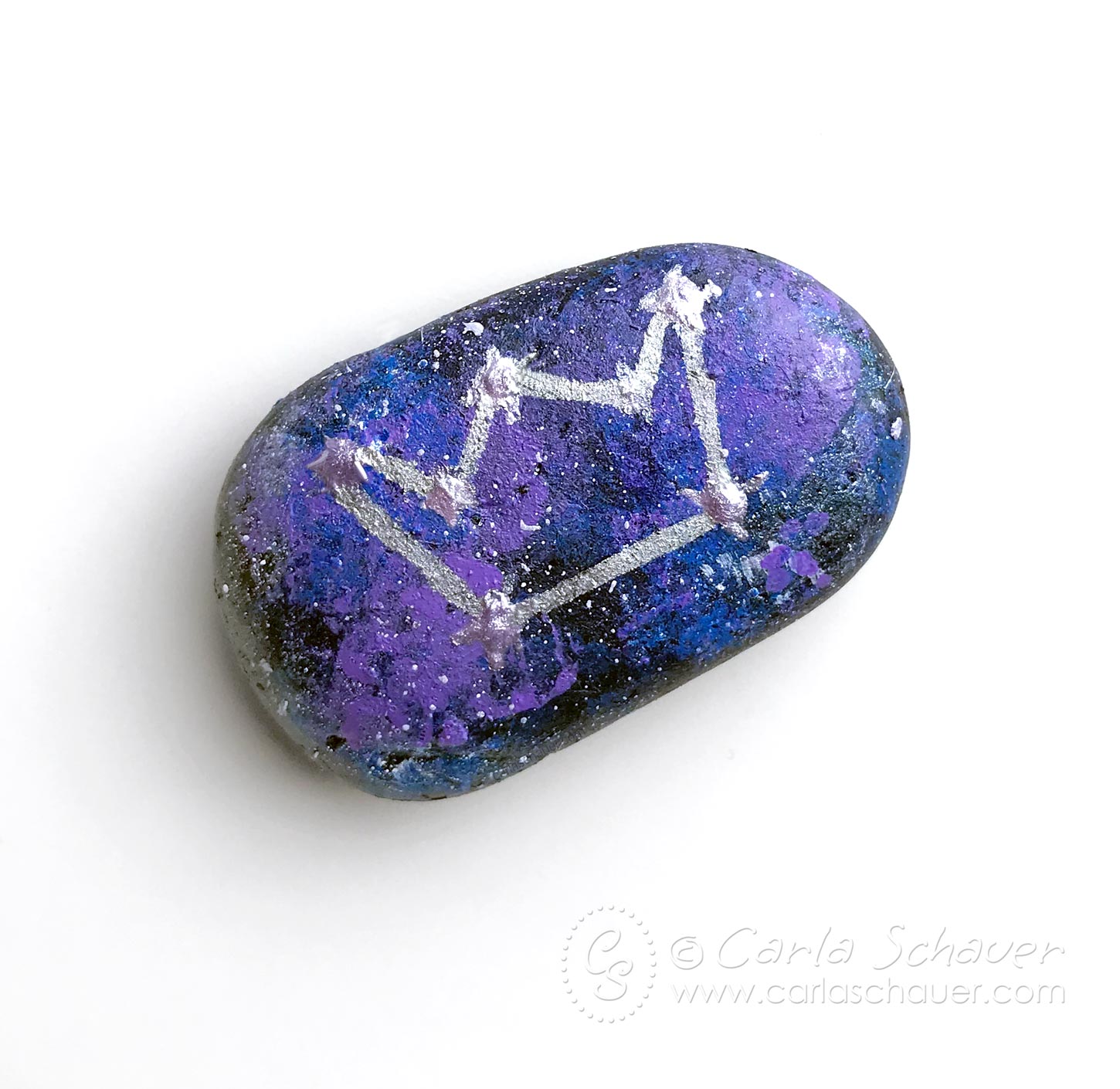 Rock painted with galaxy on white background.