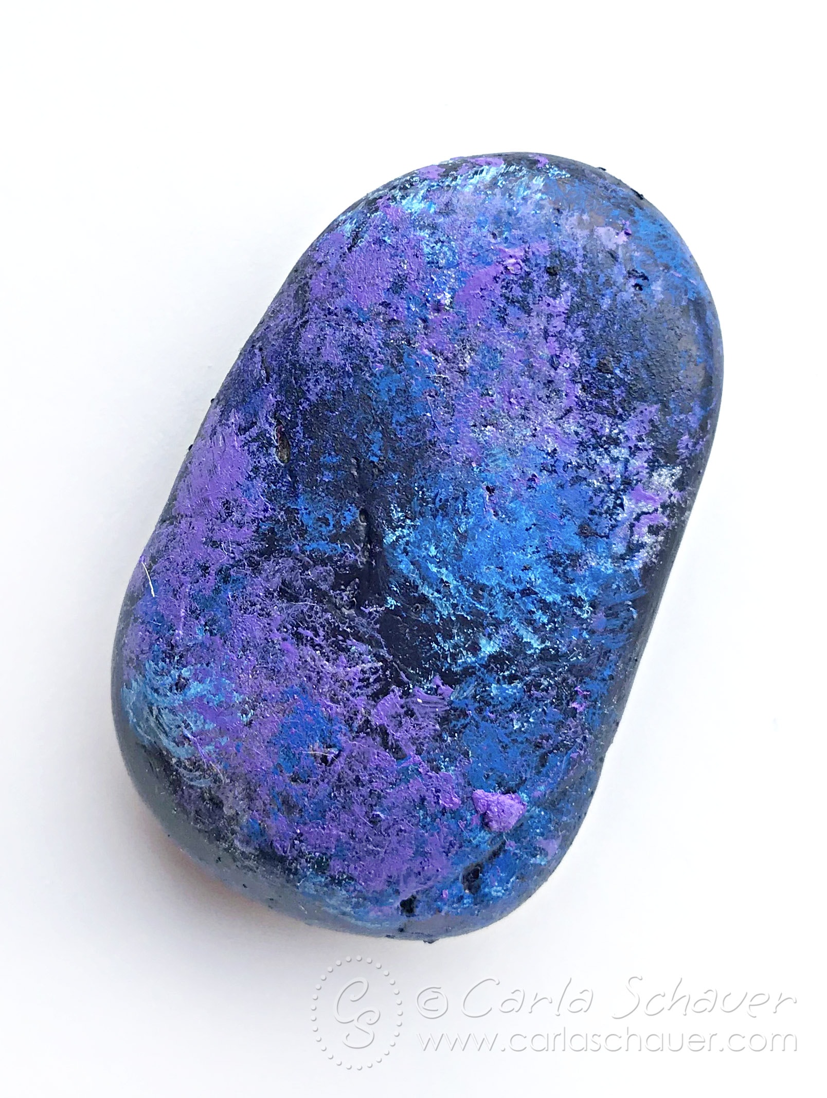 Purple, blue, and black sponge painted rock on white background