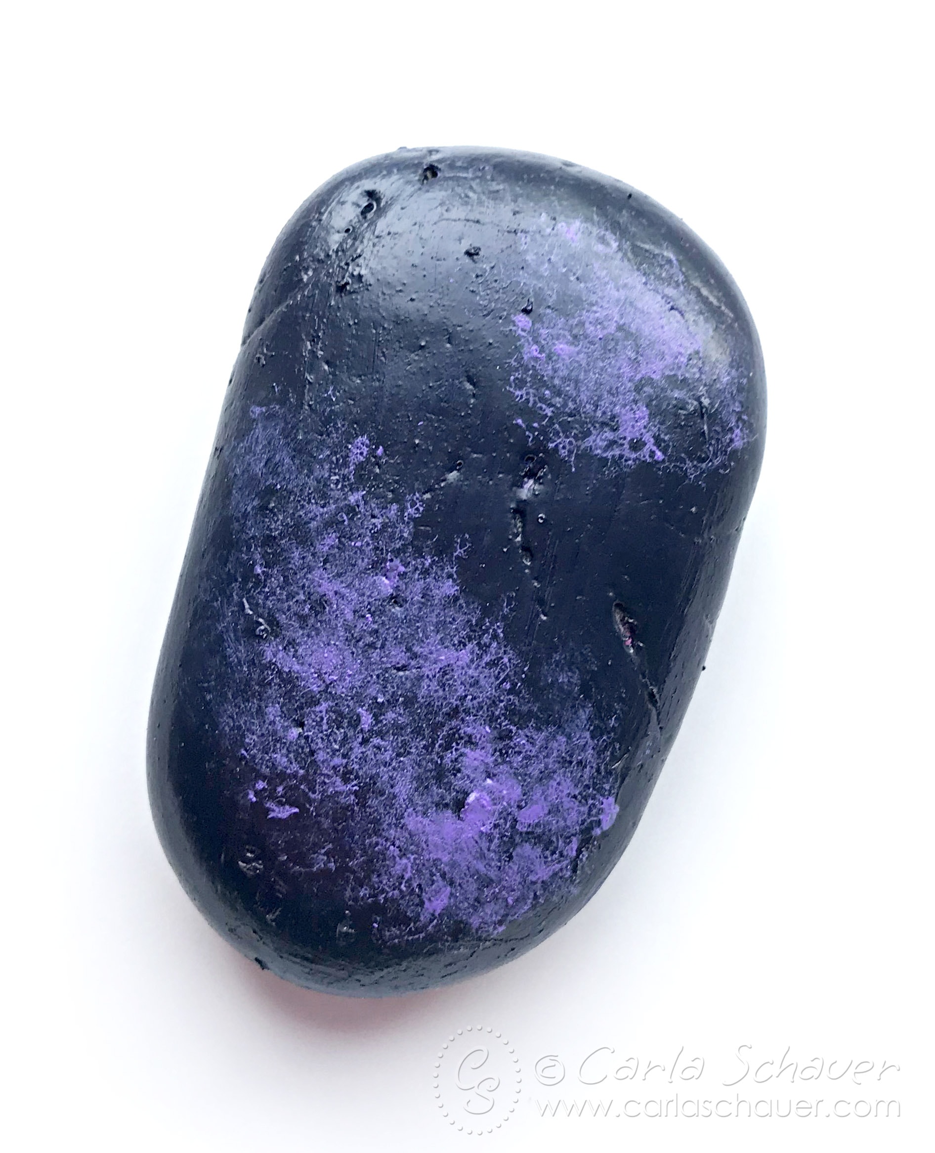 Black rock with purple sponge painting, on white backgroun
