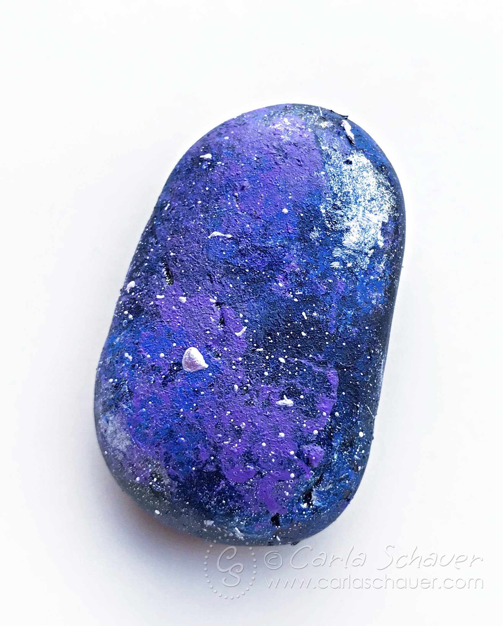 Rock painted to look like a galaxy on white background.