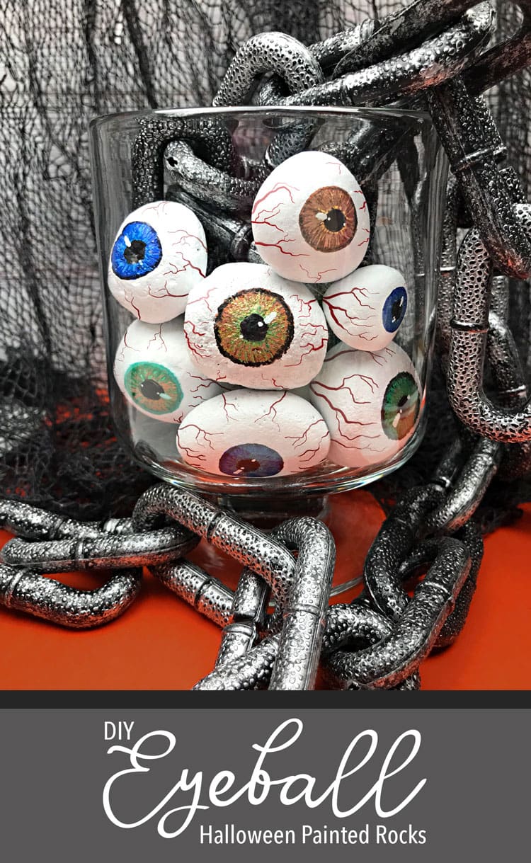 Painted rock eyeballs in jar with chain and black mesh background.