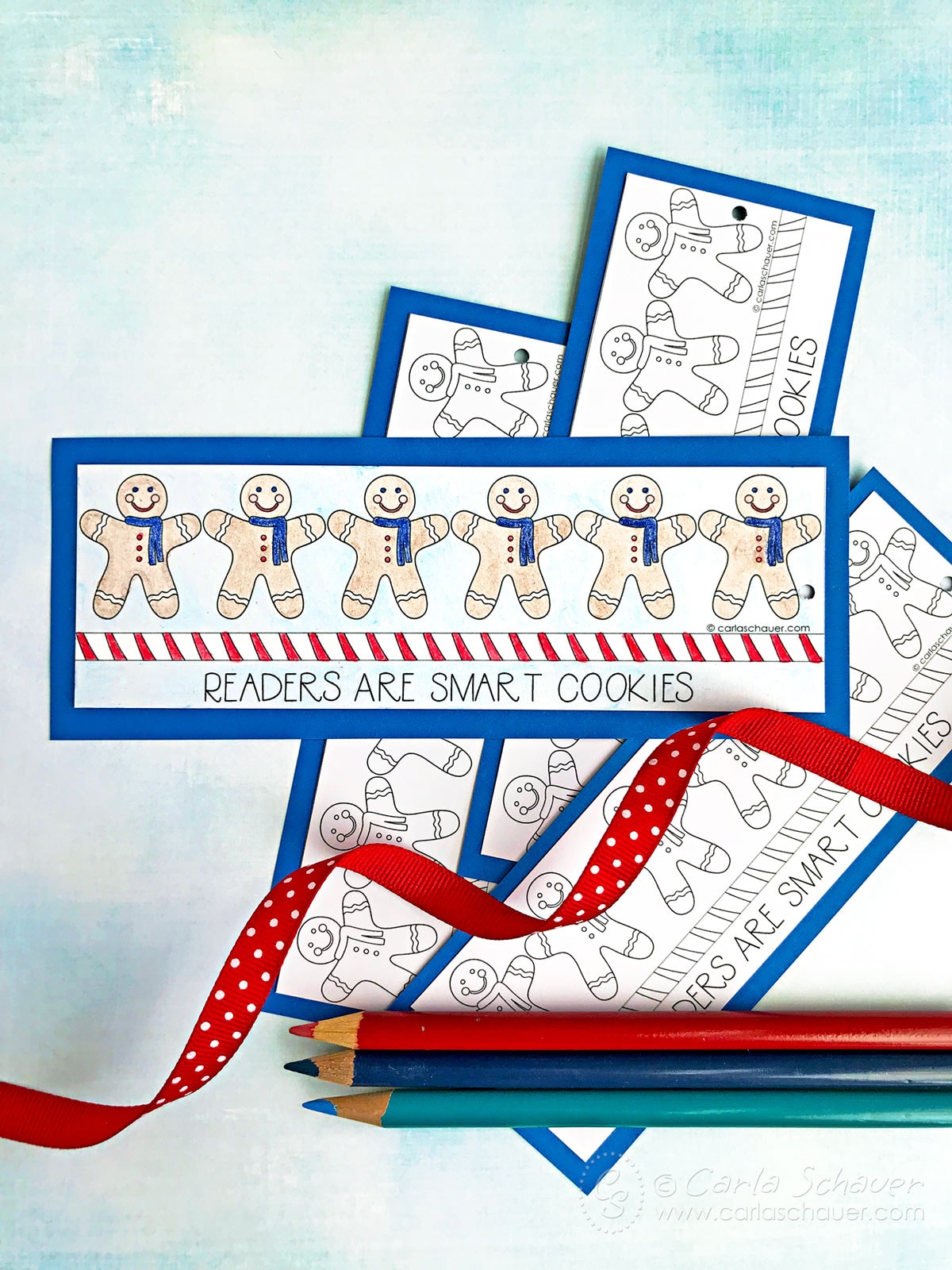 Gingerbread men colored bookmark in front of uncolored bookmarks and colored pencils.