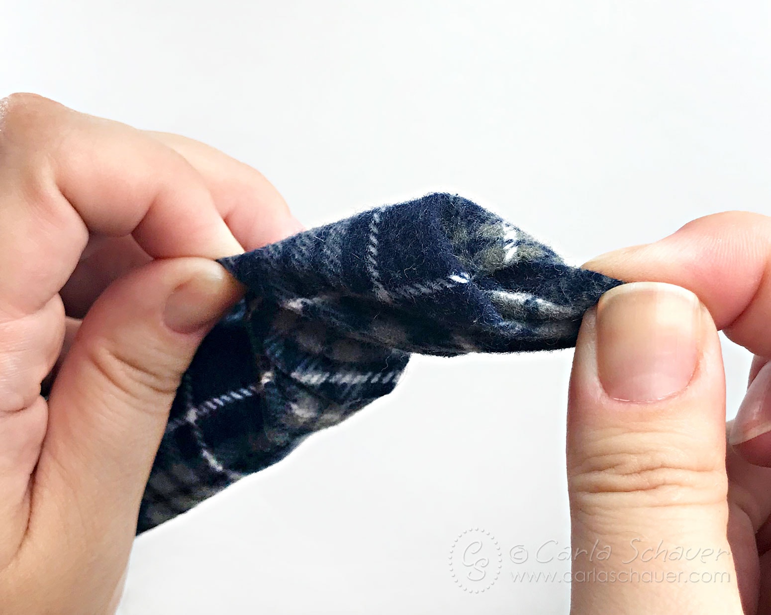 Blue plaid flannel fabric tube being with white background.