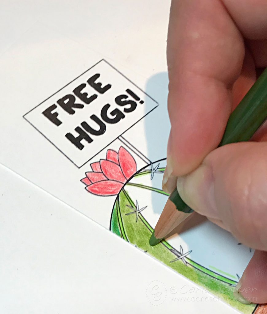 Coloring cactus bookmark with green colored pencil. Cactus has a pink flower and a sign reading "Free Hugs!"