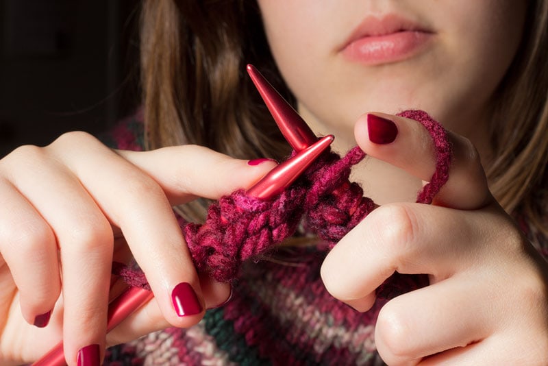 hands knitting a red scarf