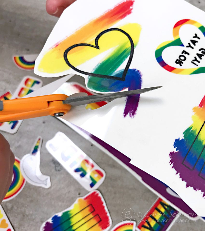 Cutting out a rainbow heart from tattoo paper.