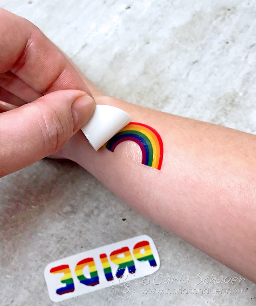 Peeling transfer paper from rainbow tattoo.