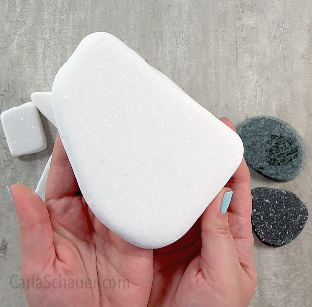 Hands holding large white Santorini Stone for painting.