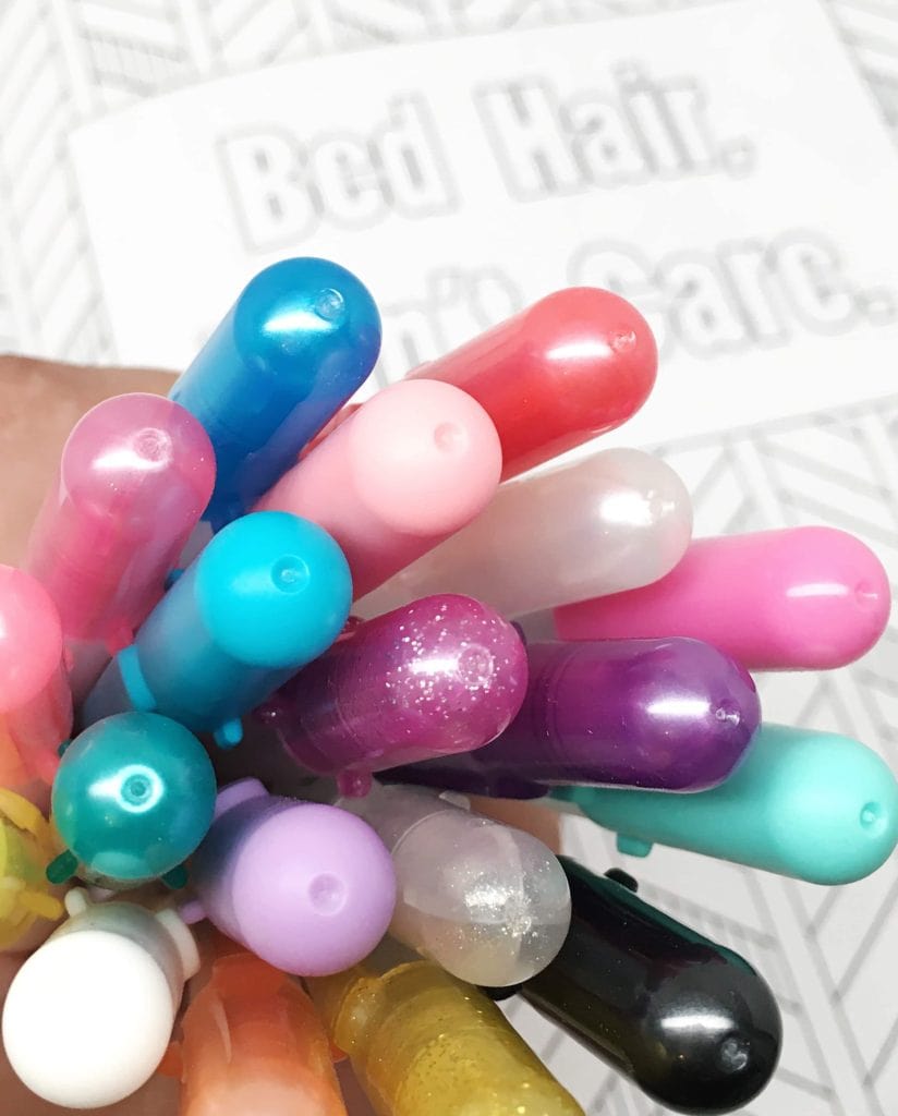 A hand full of gel pens in assorted colors, held in front of a snarky coloring page.