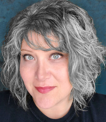 headshot of Carla Schauer, woman with green eyes and wavy white and brown hair.