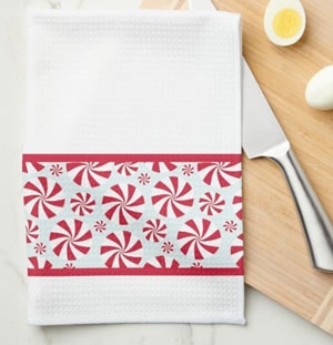 white kitchen towel with red and aqua peppermint candy pattern stripe, sitting on wood cutting board with knife